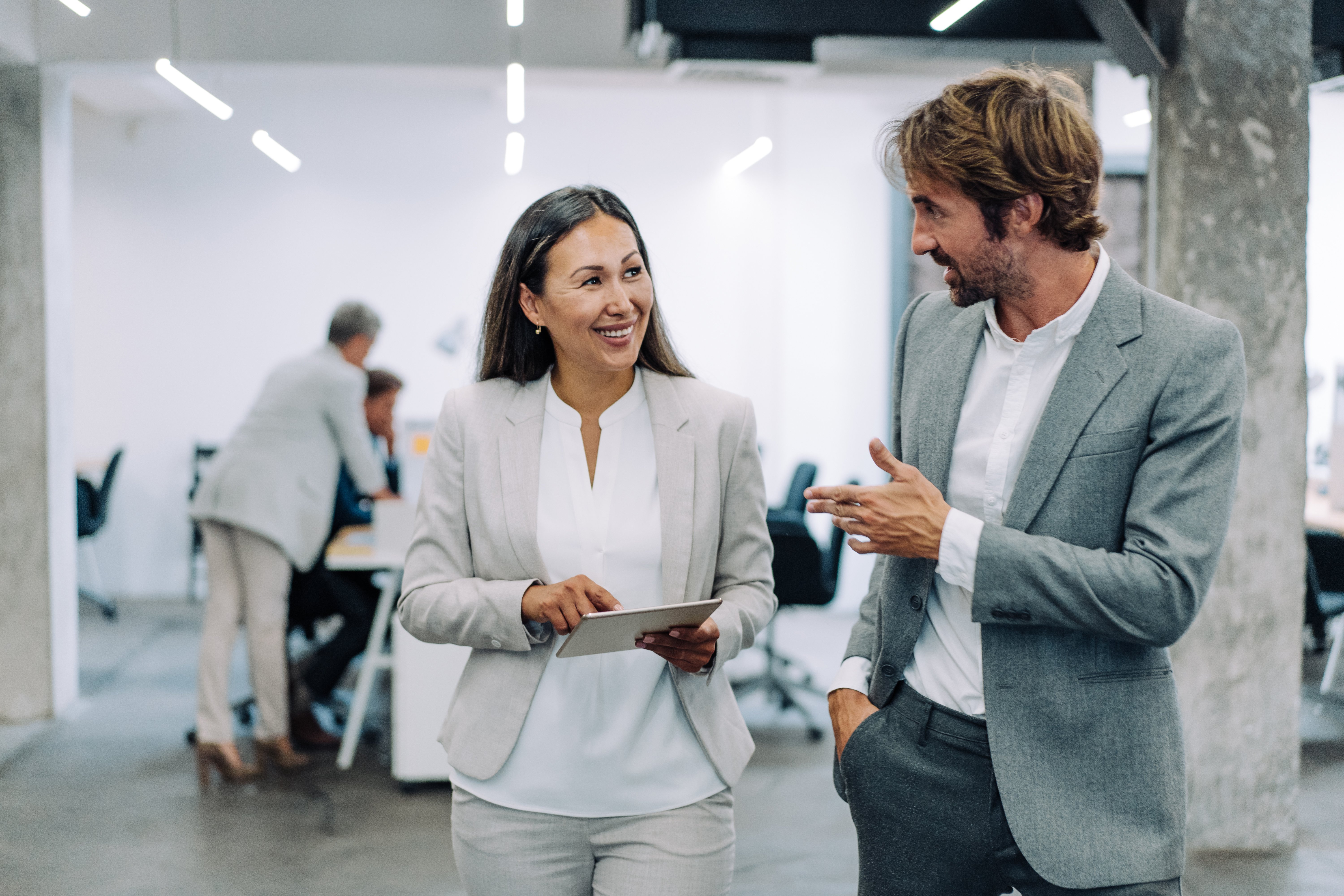 Two business people in discussion while walking with a tablet