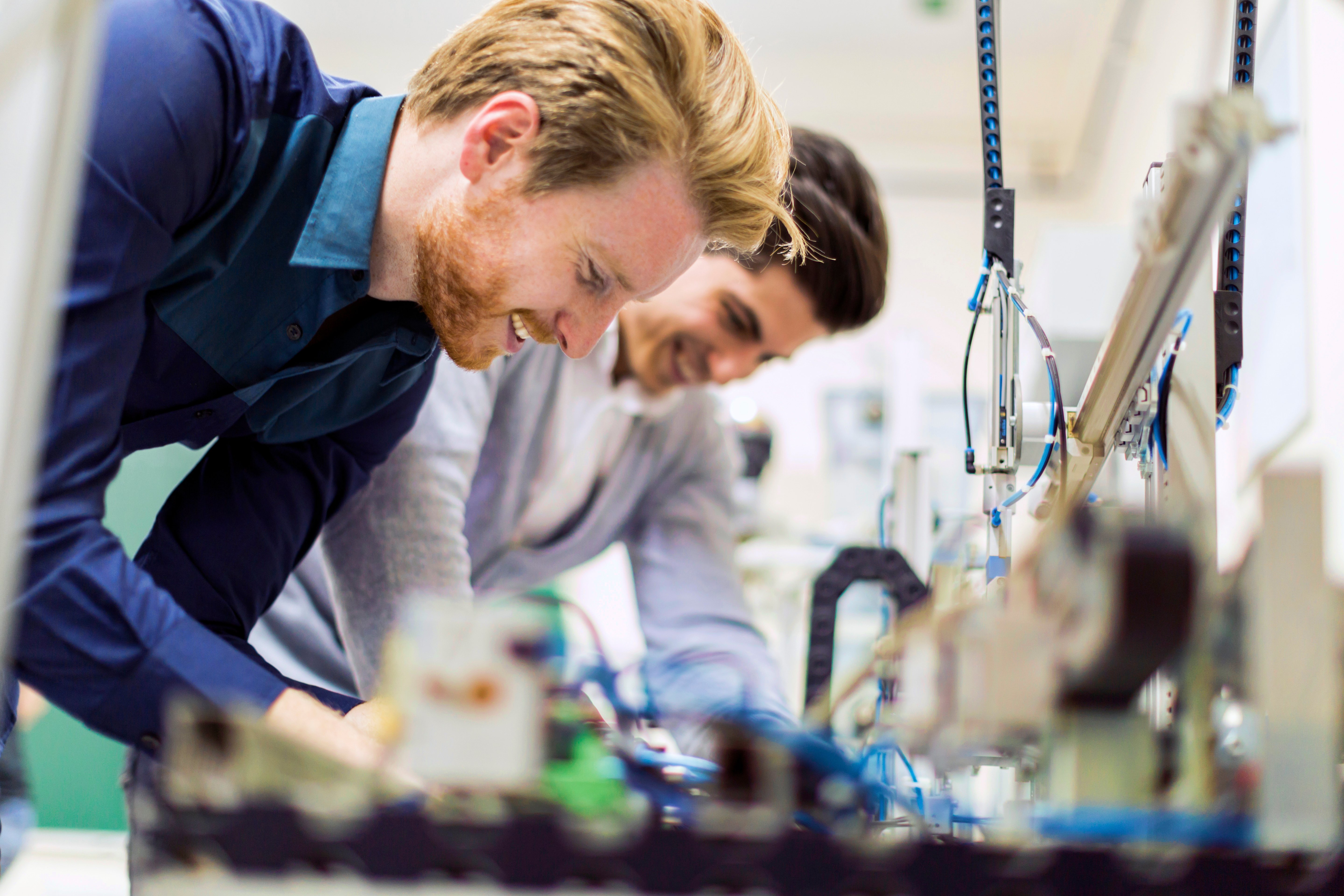 Two smiling men work on electronics